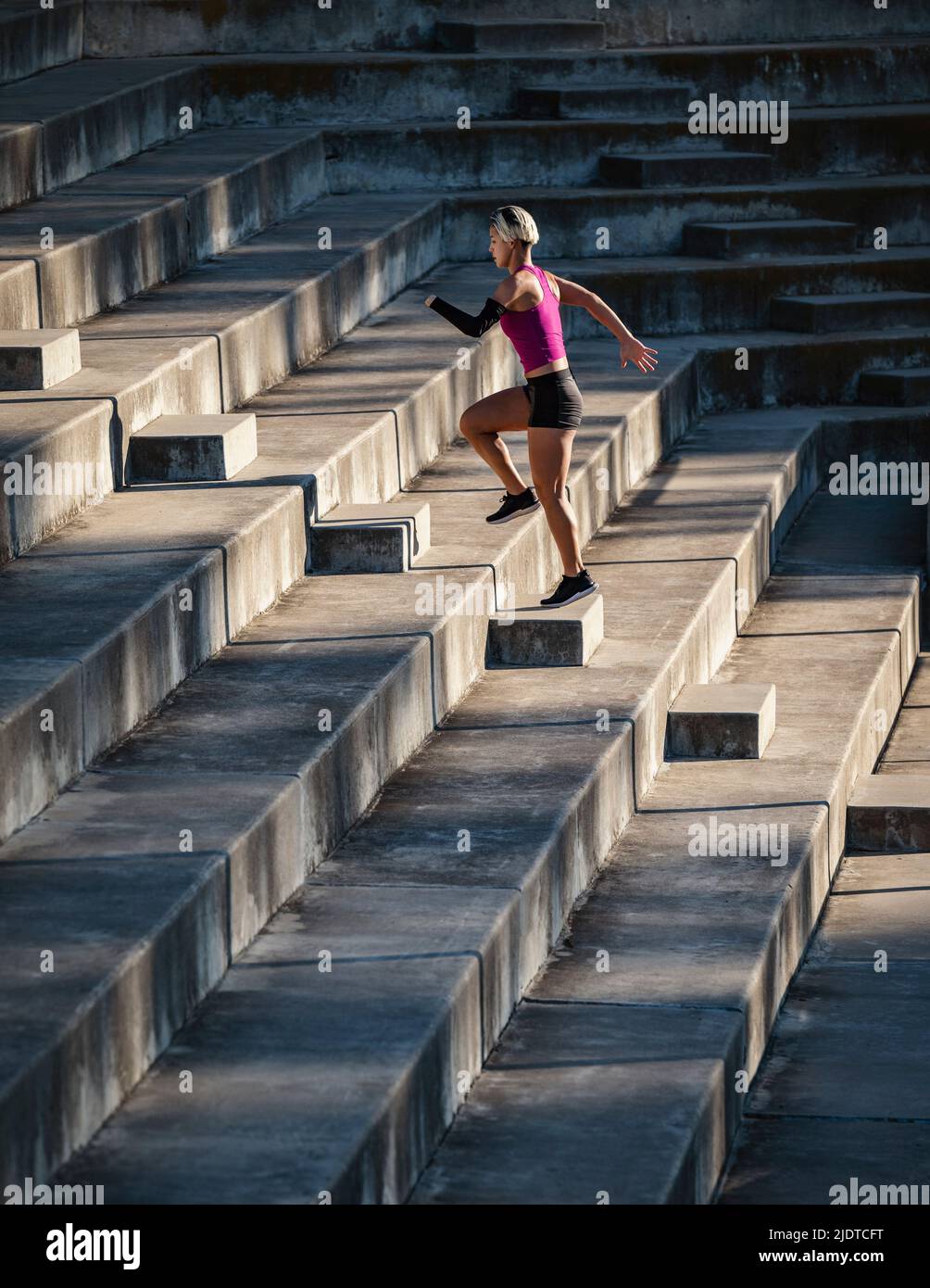 Athletic woman with amputated hand running up steps Stock Photo