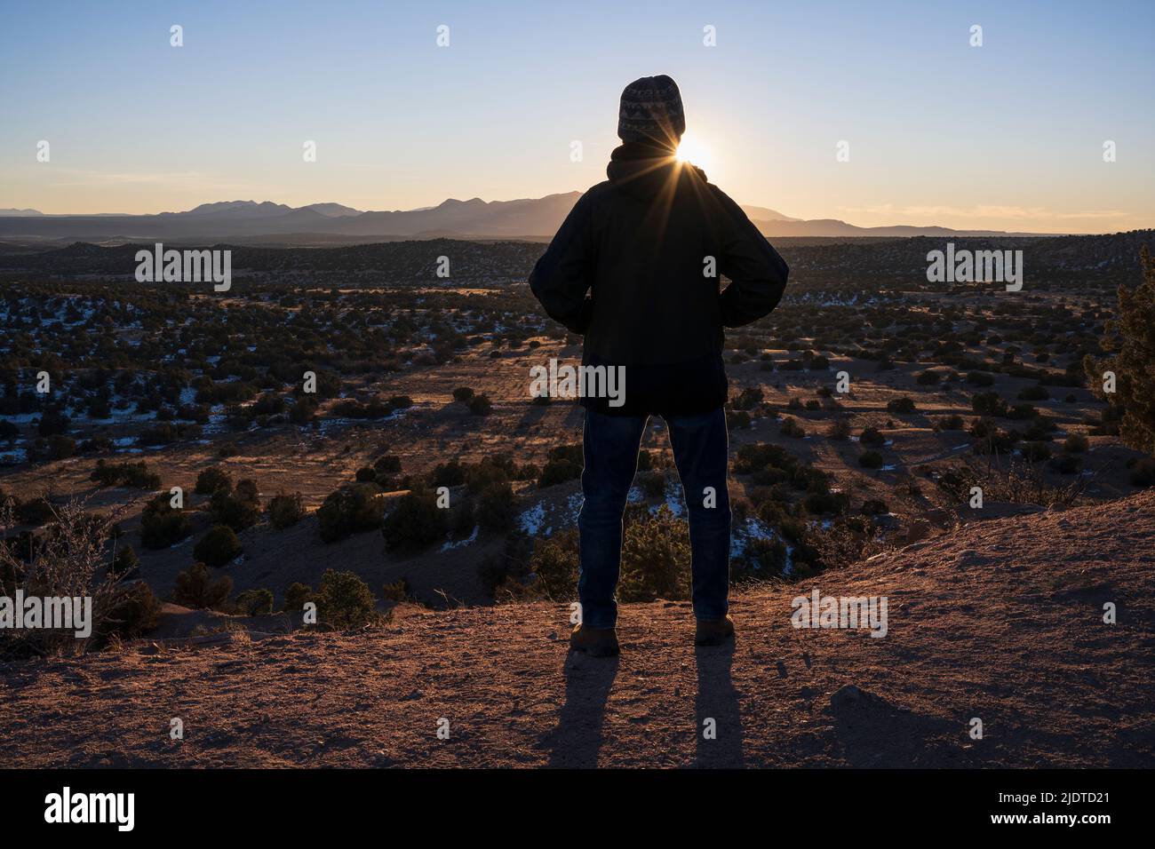 USA, New Mexico, Lamy, Rear view of man in desert landscape at sunset in Galisteo Basin Preserve Stock Photo