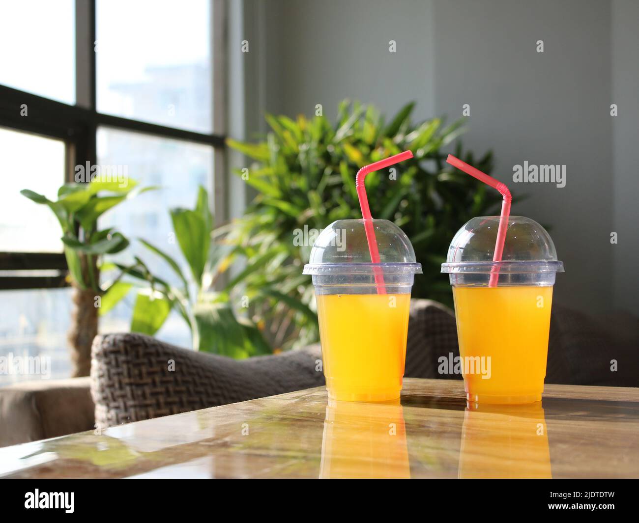 Yellow juice glasses or plastic disposable glasses with straws on table
