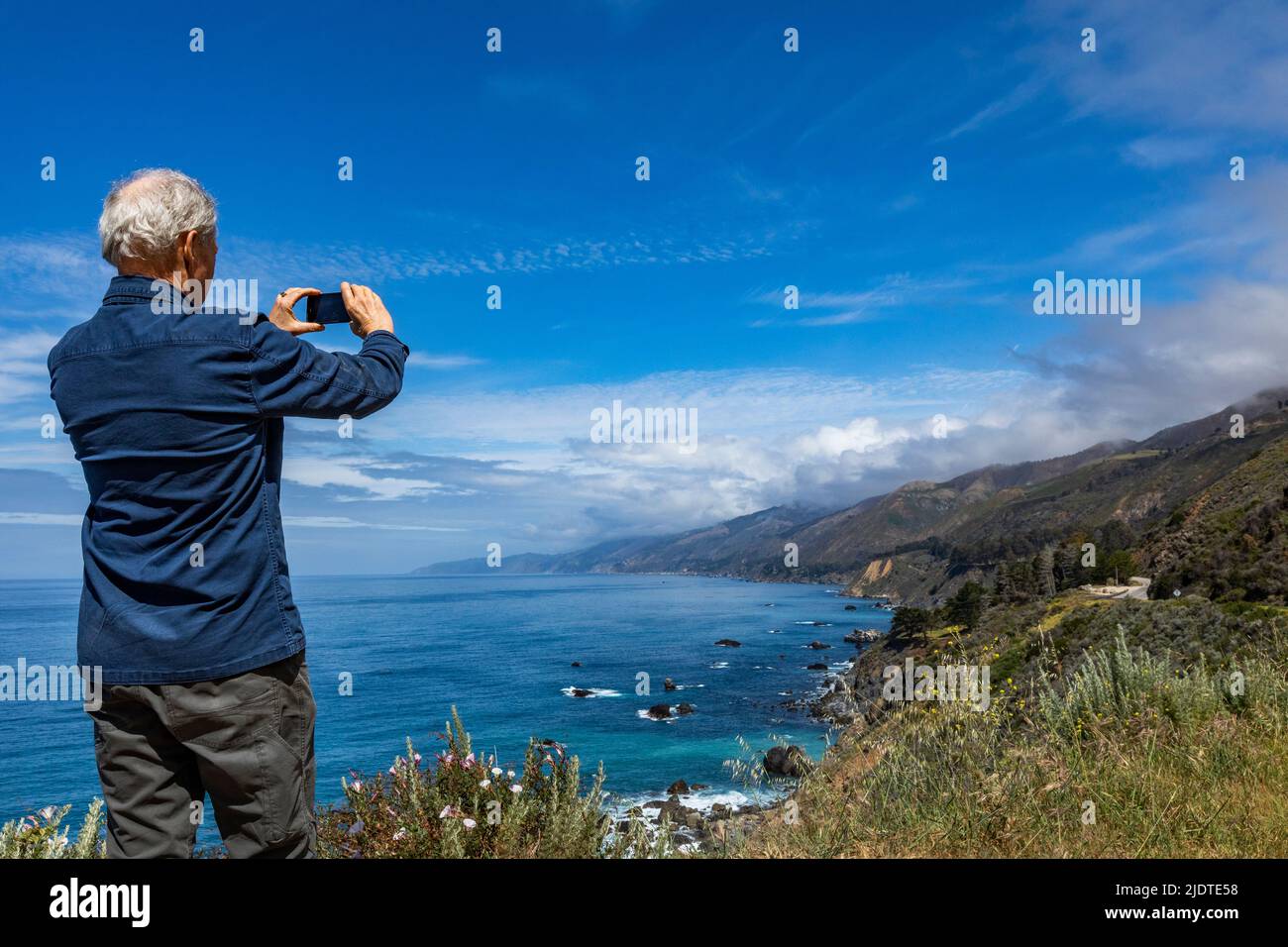 USA, California, Big Sur, Rear view of senior man photographing Big Sur coast Stock Photo