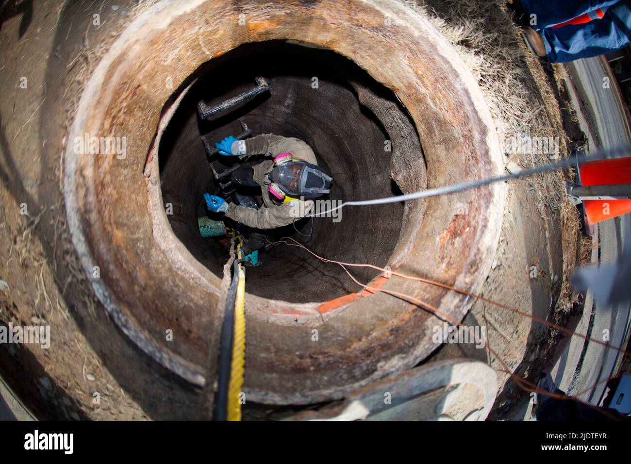 Worker in manhole installing cable for utility company Stock Photo