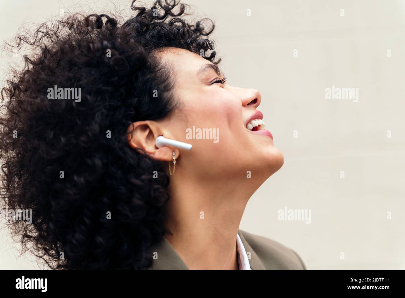 portrait of a happy woman with wireless earphones laughing and enjoying listening to music, concept of youth and technology, copy space for text Stock Photo