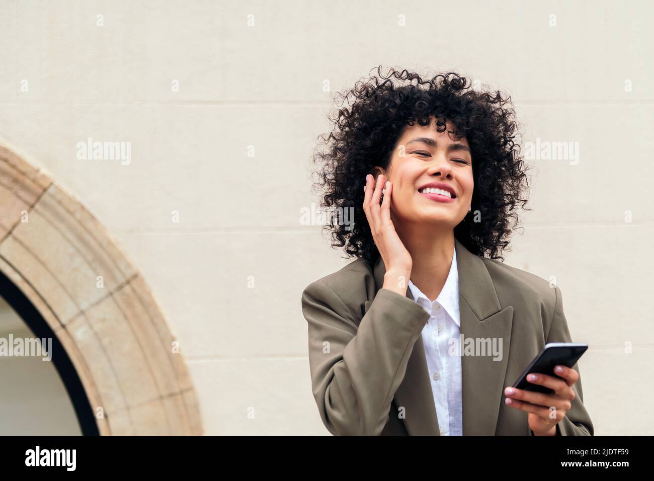 happy woman with wireless earphones enjoys listening to music with her phone, concept of youth and technology, copy space for text Stock Photo
