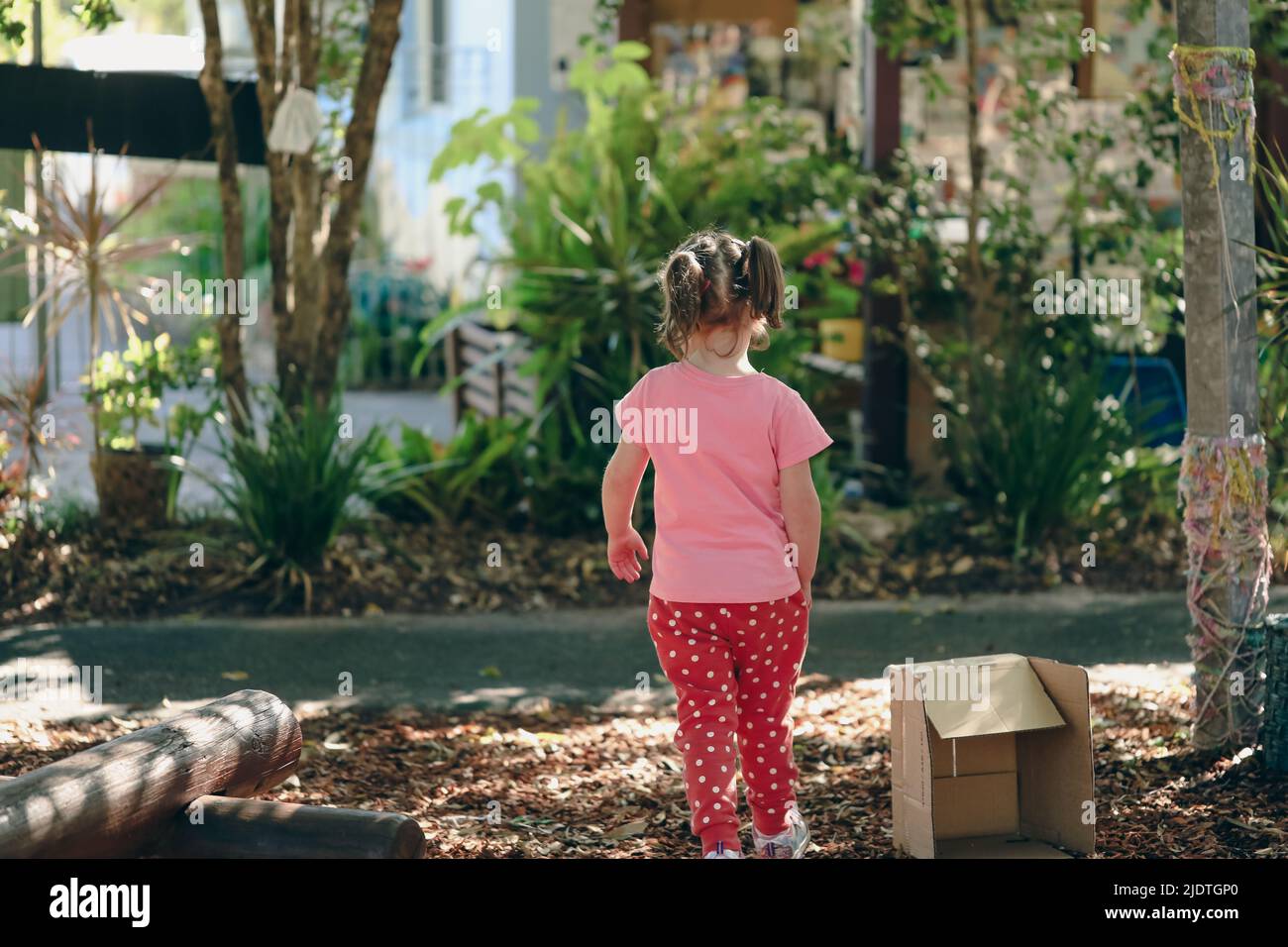 Little preschool girl with pigtails exploring garden outdoors at