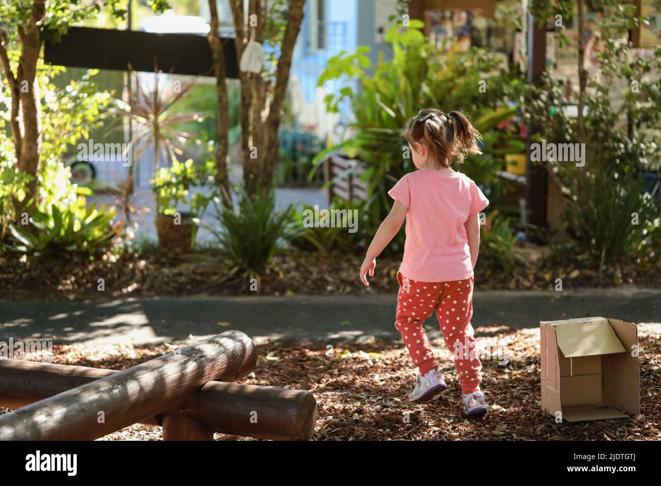 Little preschool girl with pigtails exploring garden outdoors at