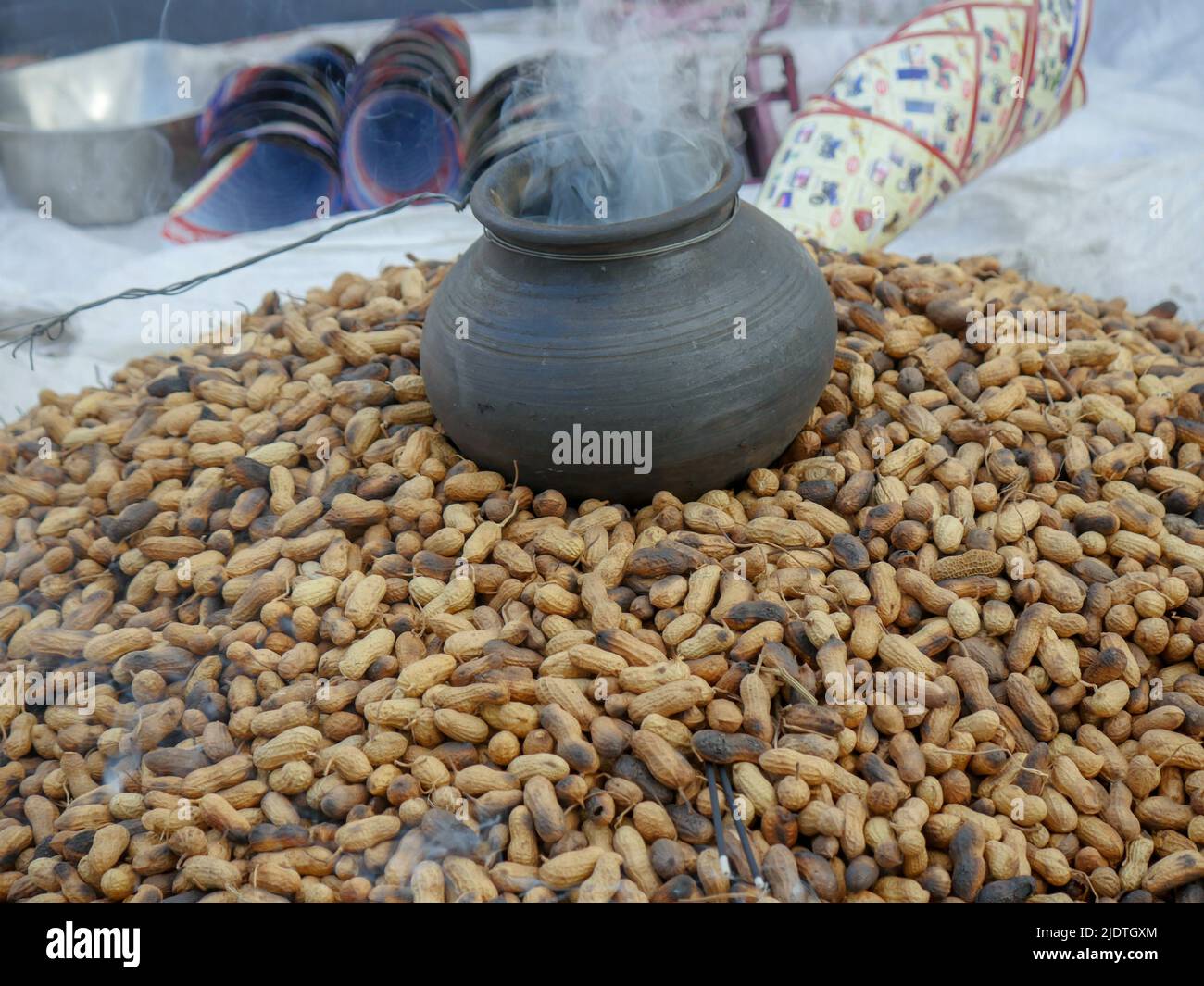 Heap of roasting raw peanuts, Smoke coming out of pot with peanuts below. peanut also known as the groundnut, goober, pindar or monkey nut. Stock Photo