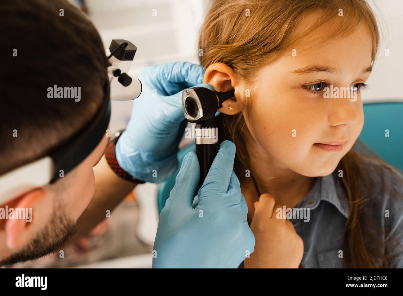 ENT doctor otolaryngologist looks through otoscope the ears of a little