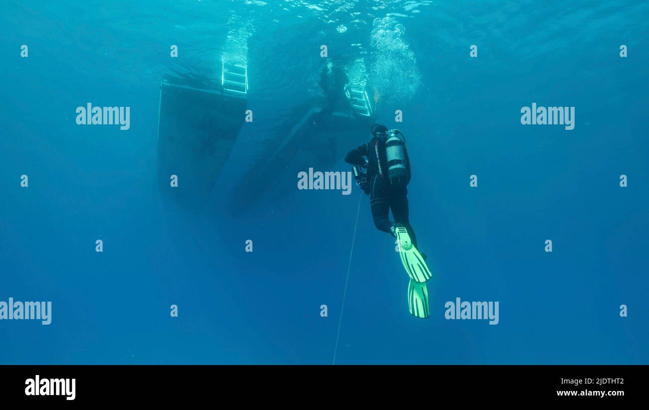 Scuba diver swim towards diving boat in blue water. Mediterranean Sea, Cyprus Stock Photo