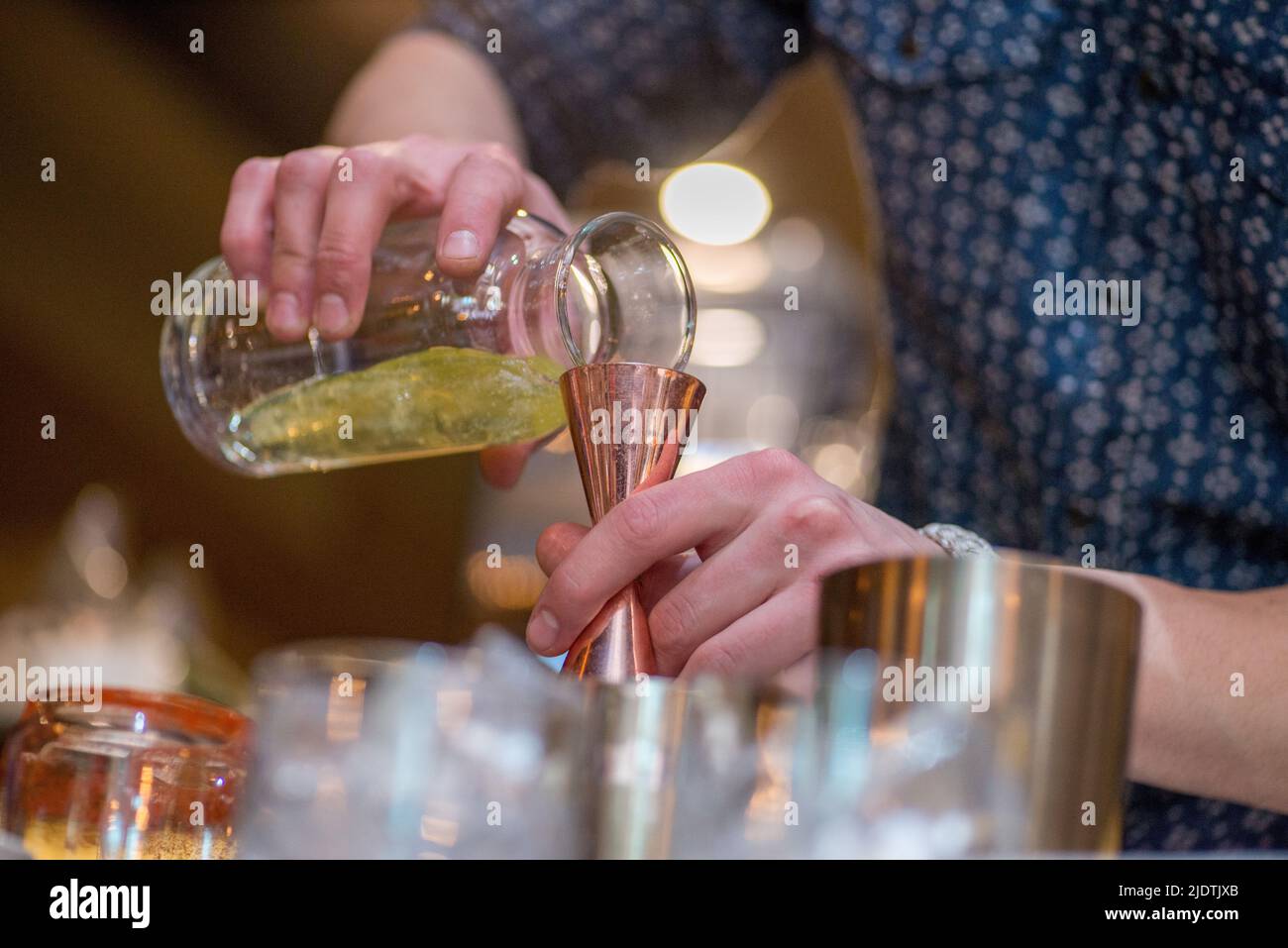 barman preparing cocktai and  pours liquid into the jigger in a cocktail bar Stock Photo