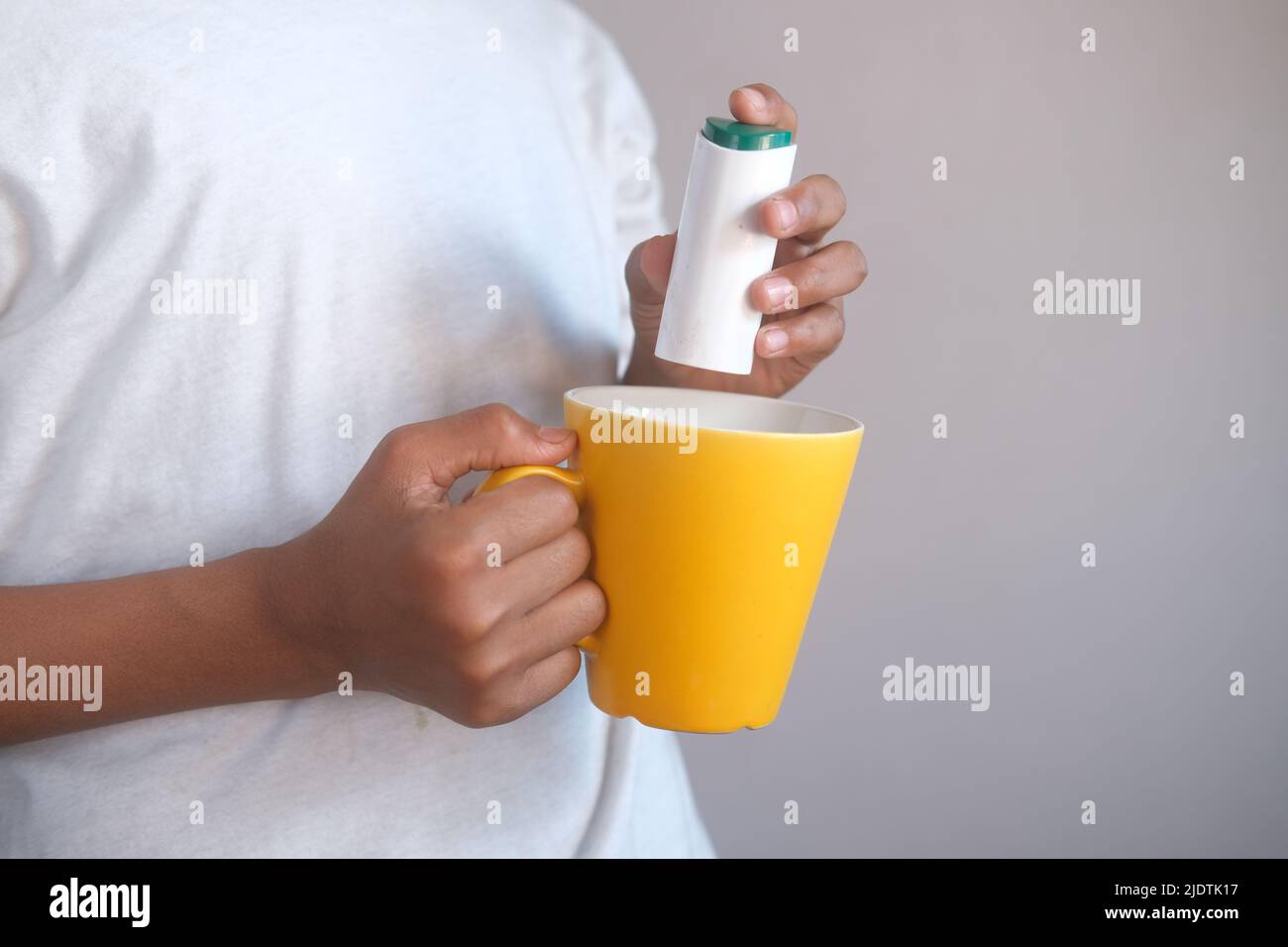 young man putting artificial sweetener in tea, Stock Photo