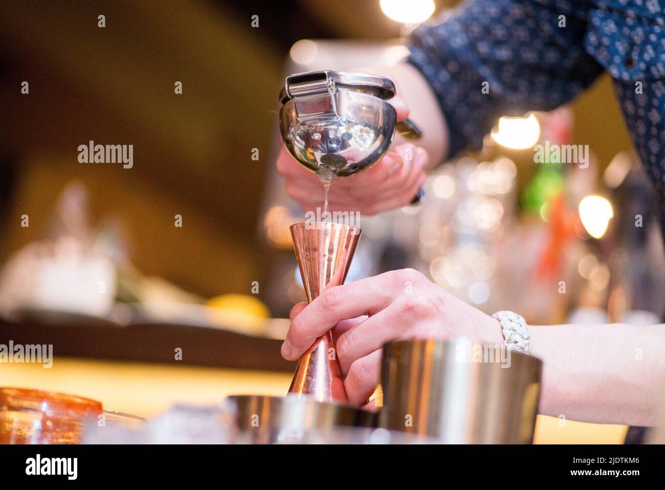 barman preparing cocktai and  pours liquid into the jigger in a cocktail bar Stock Photo