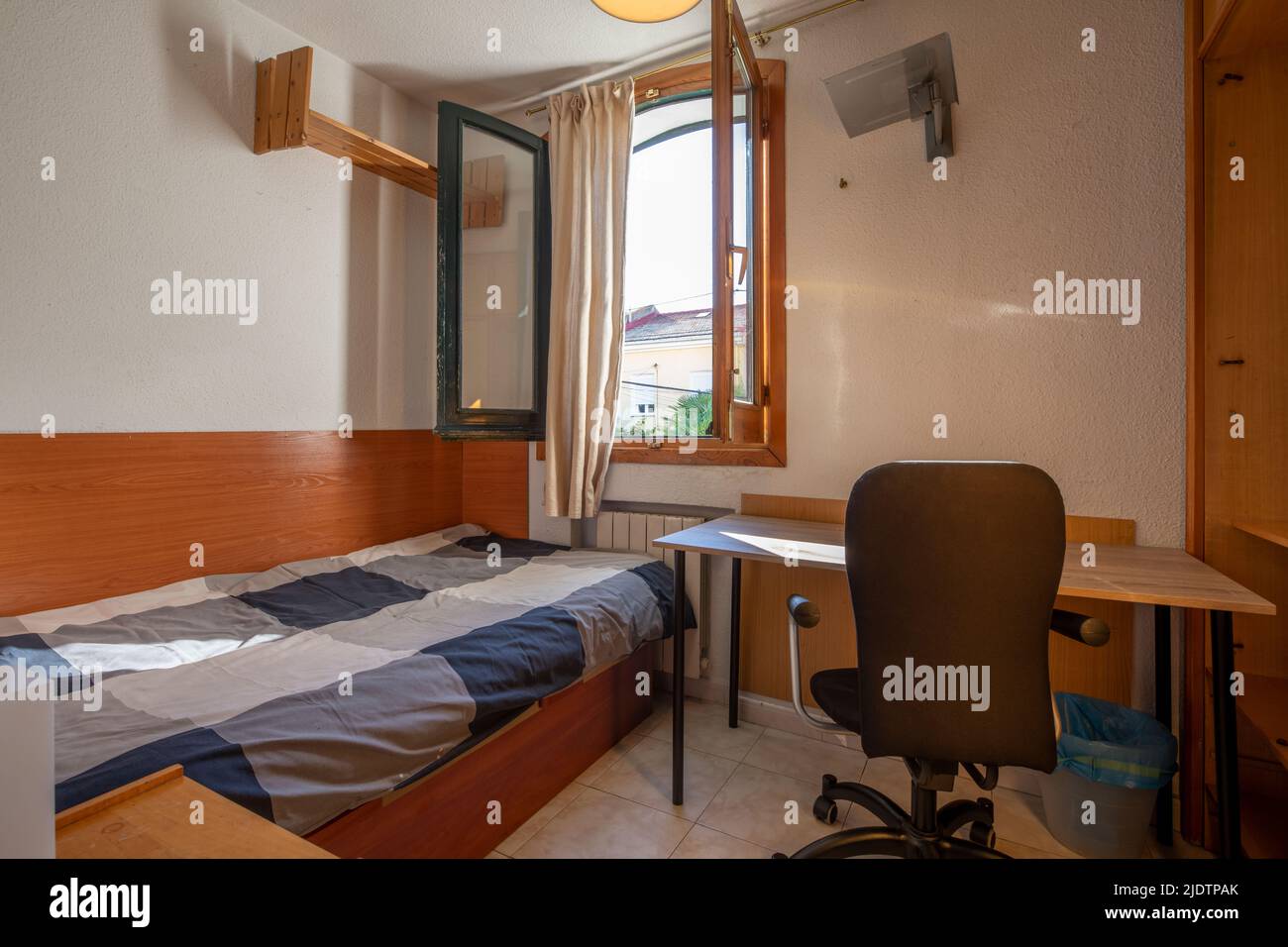 Small bedroom with single bed, study table and wooden window with views ...