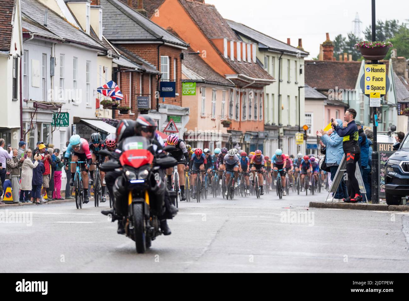 UCI Women's Tour international cycle race peloton passing through the High Street of the market town of Hadleigh in Suffolk, UK, in bad weather. Rain Stock Photo