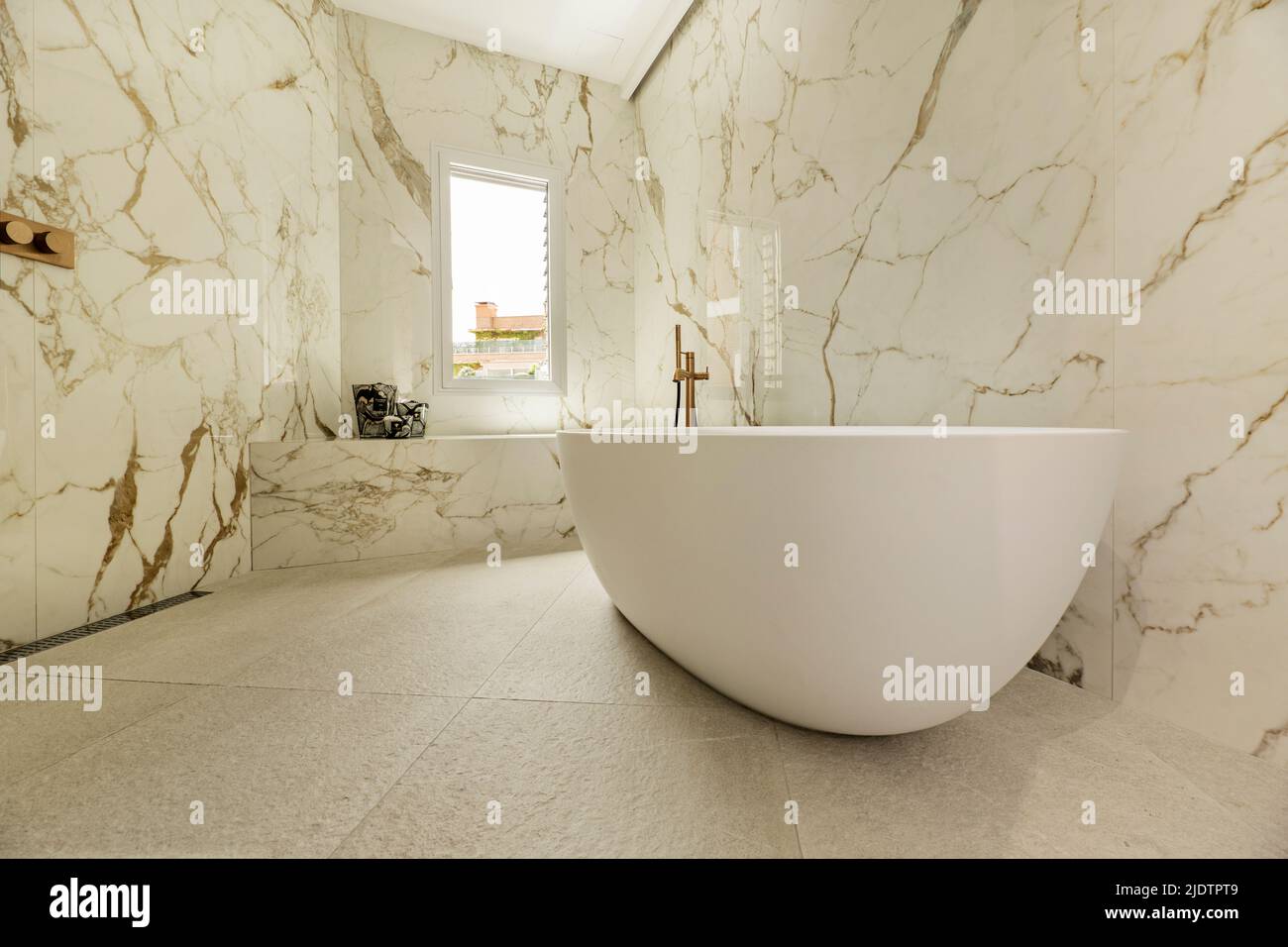 Detail of a bathroom with marble walls, continuous worktop in the same