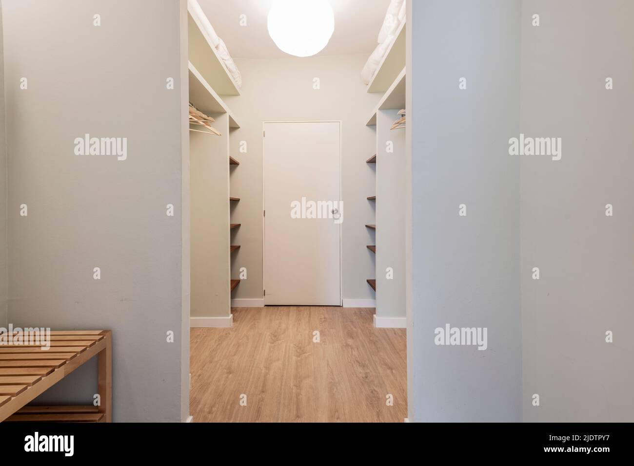 Dressing room of a bedroom with gray painted walls, wooden shelves and