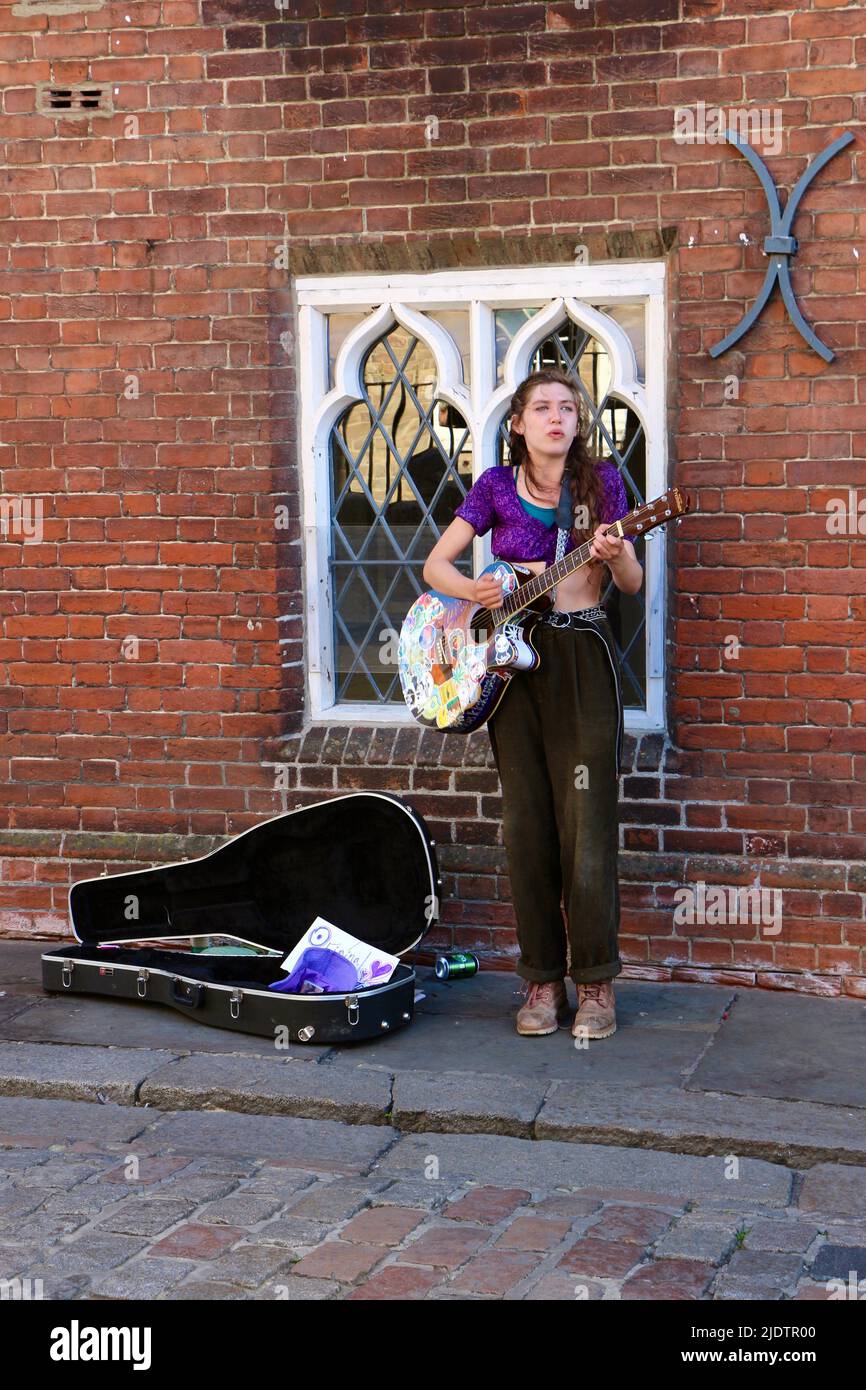 A woman playing guitar and singing busking in the street Canterbury Kent England UK Stock Photo