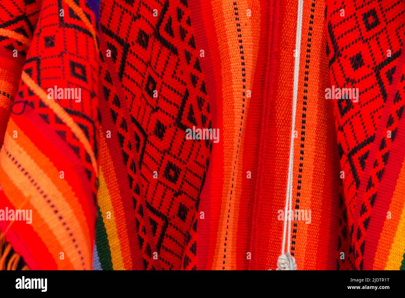 Red and black patterns over some clothes made of llama wool at Cusco souvenirs shop, Peru. Stock Photo
