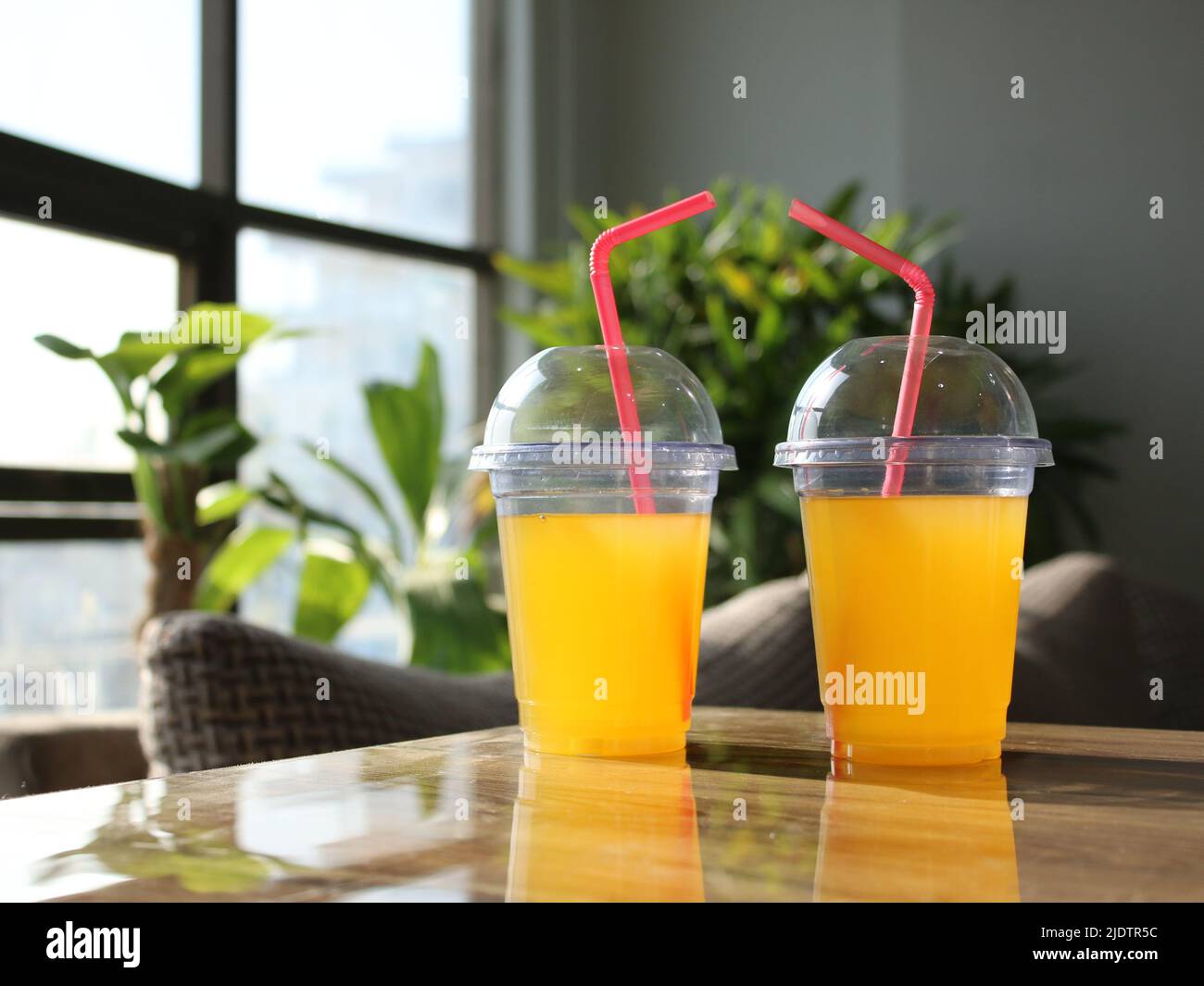 Yellow juice glasses or plastic disposable glasses with straws on table