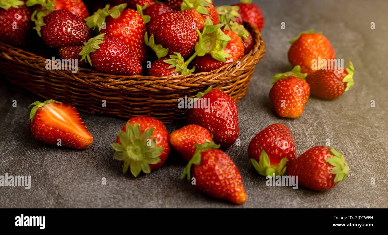 Ripe juicy strawberries in a basket on a dark background. Close up. Stock Photo
