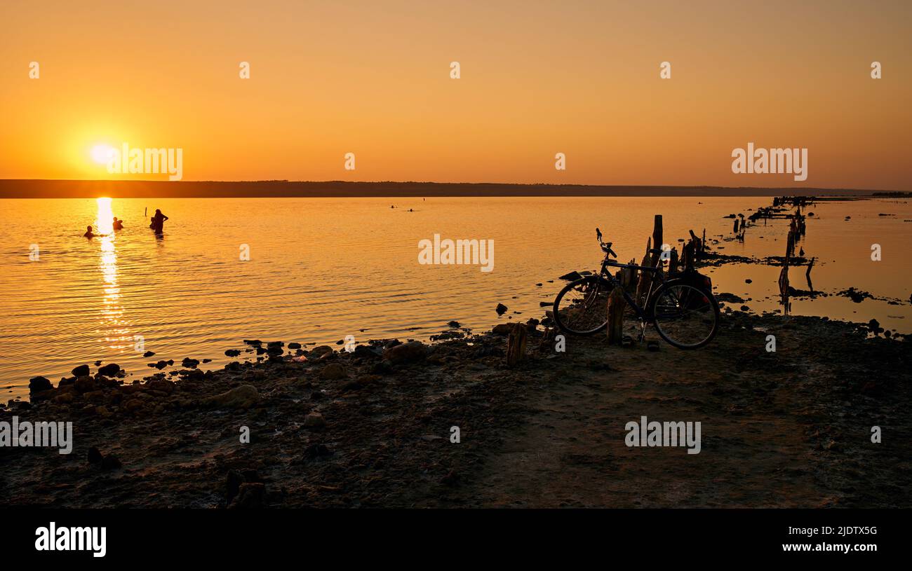 Beautiful sunset on the Kuyalnik Estuary with swiming people in Odessa, Ukraine. Stock Photo