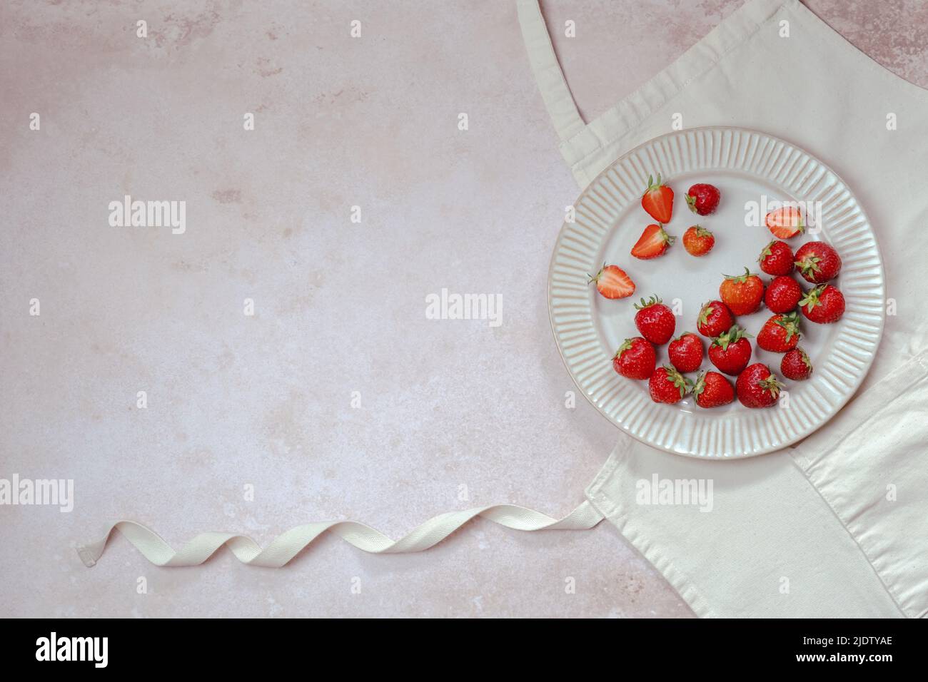 Recipes for summer holiday baking. Strawberries in a plate on a mockup apron. text background, sweet pastries. top view. Stock Photo