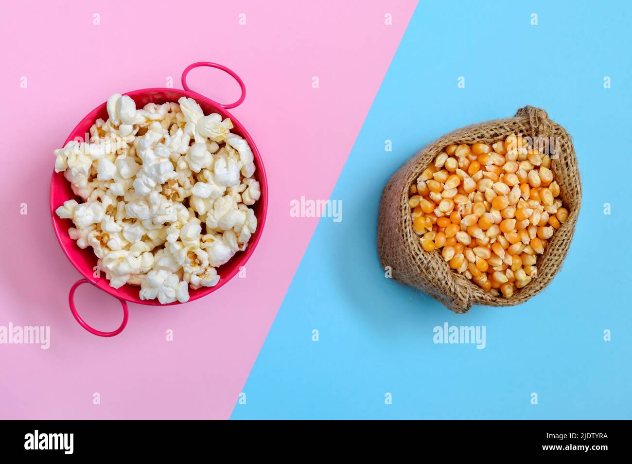 A bowl of popcorn and a bag of corn kernels on a bicolor background