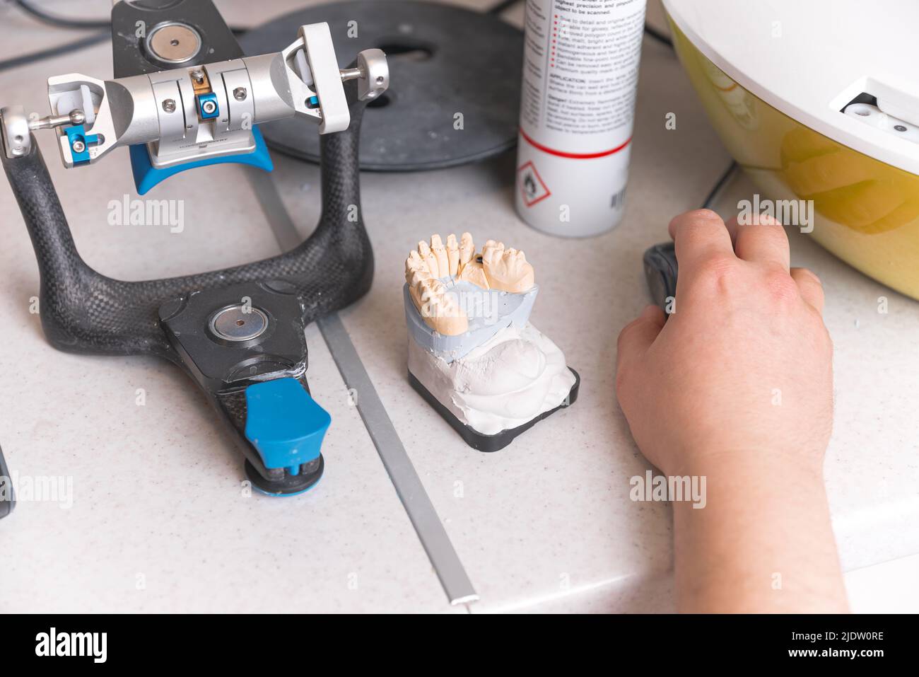 Work table of a dentistry technician with his hand on his mouse near