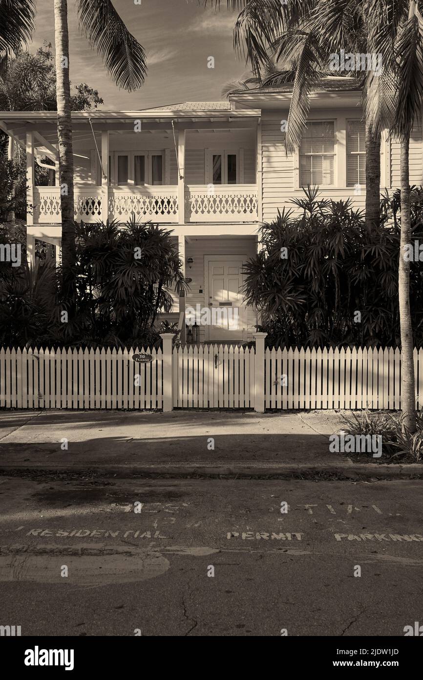 Beautiful Conch style home in the Old Town section in Key West, Florida, USA.  Surrounded with a white picket fence and palm trees.  Stark contrast. Stock Photo