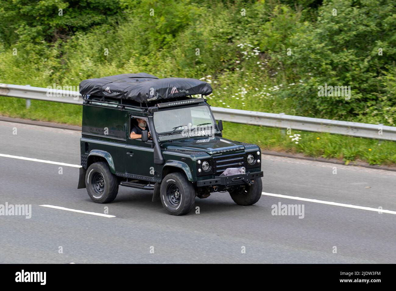 2002 green Land Rover Defender Pick-up TD5 expedition SWB diesel truck; travelling on the M61 Motorway, Manchester, UK Stock Photo