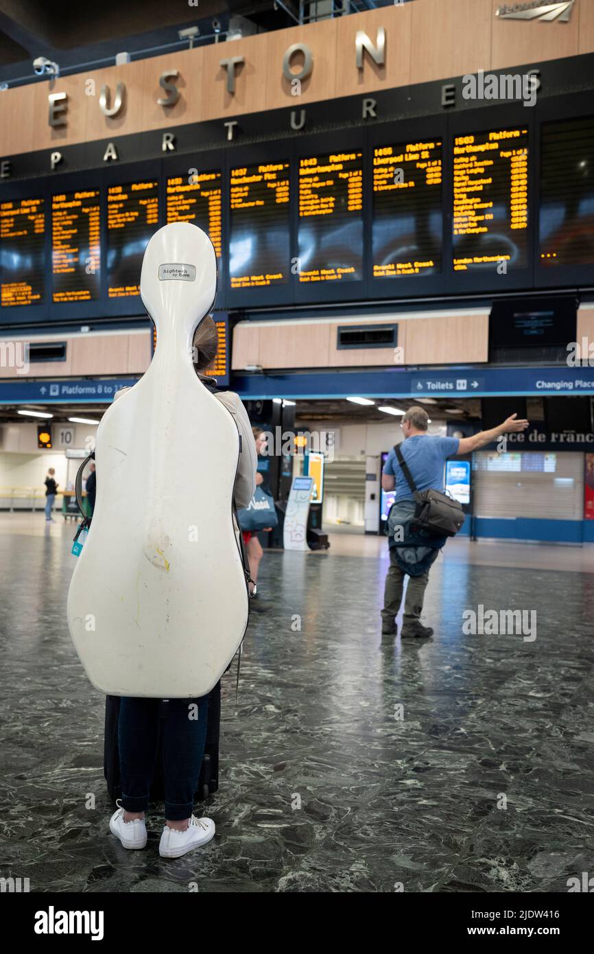 On the second day of the UK's rail strike, when railway and London Underground workers with the RMT union have taken industrial action, the most disruptive rail strike across England, Scotland and Wales for thirty years, cellist Jane Lindsay nervously waits for the last train to Glasgow from Euston station, hopefully in time for an evening performance, on 23rd June 2022, in London, England. After an earlier cancelled train and then a cancelled EasyJet flight, Jane tries for the third time to reach her concert venue. Her train is scheduled to arrive with less than an hour before the 'Don Giovan Stock Photo