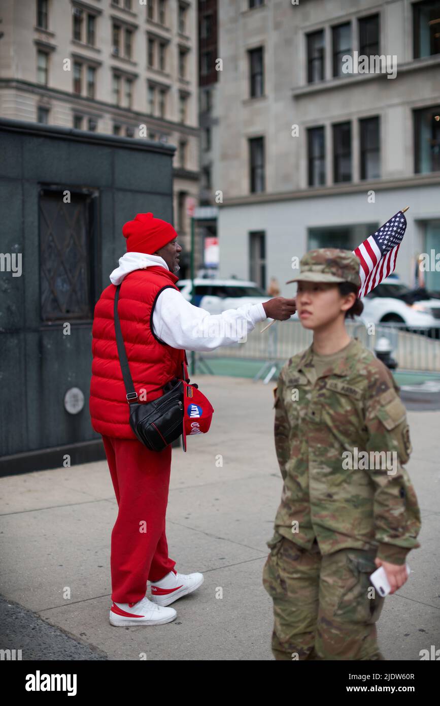 Manhattan, USA - 11. November 2021: African American Men waving US Flag, Female US Army soldier out of focus in foreground Stock Photo