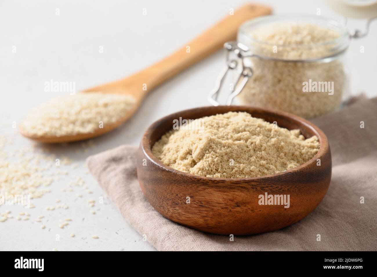 Sesame flour in bowl and sesame seeds in spoon. Stock Photo