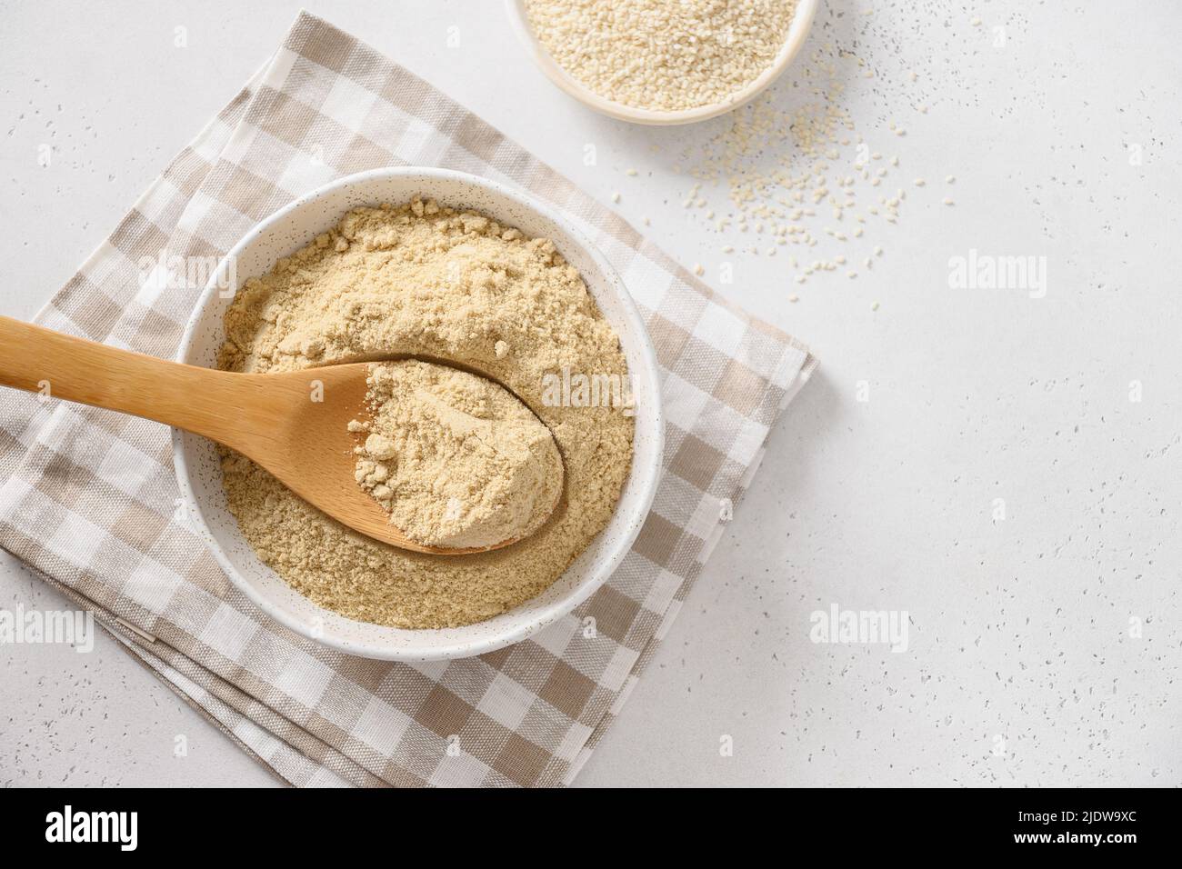 Sesame flour in wooden spoon on white. Stock Photo