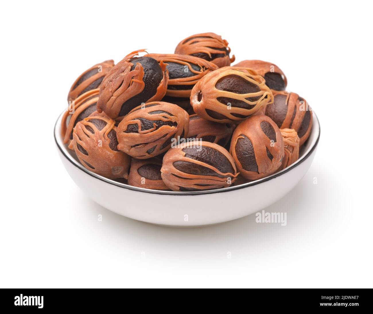 Whole nutmegs with mace in ceramic bowl  isolated on white Stock Photo