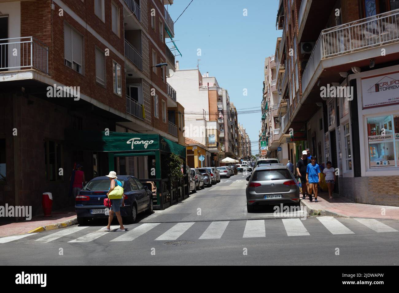 Tourists and pedestrians walking at a crossing in a seaside city street,  Torrevieja, Spain. Europe summer travel vacation. Stock Photo
