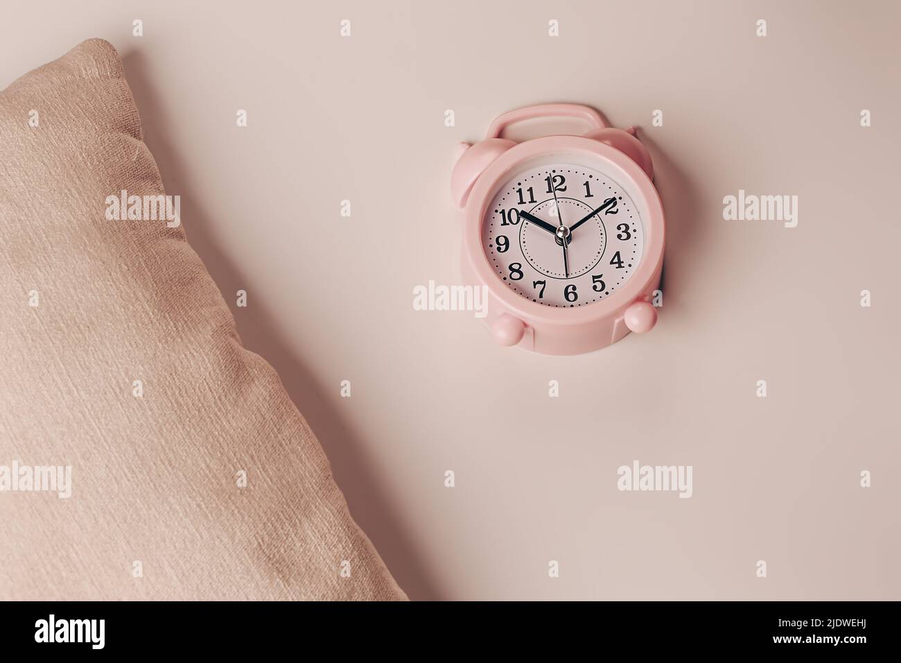 Pillow and alarm clock on a beige background. Healthy restful sleep concept. Stock Photo