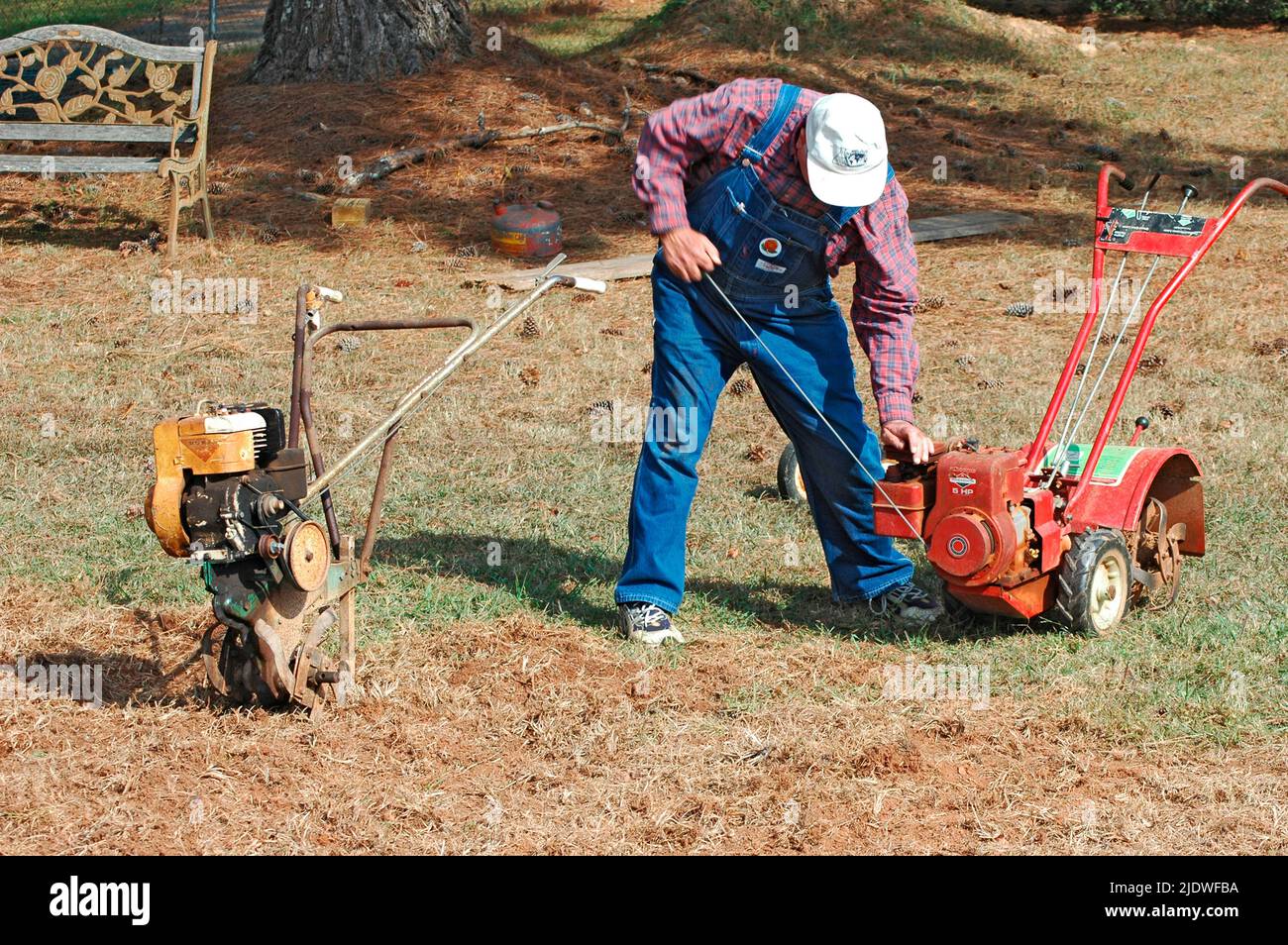 Men roto tilling a lawn to put in garden with tillers, front and rear
