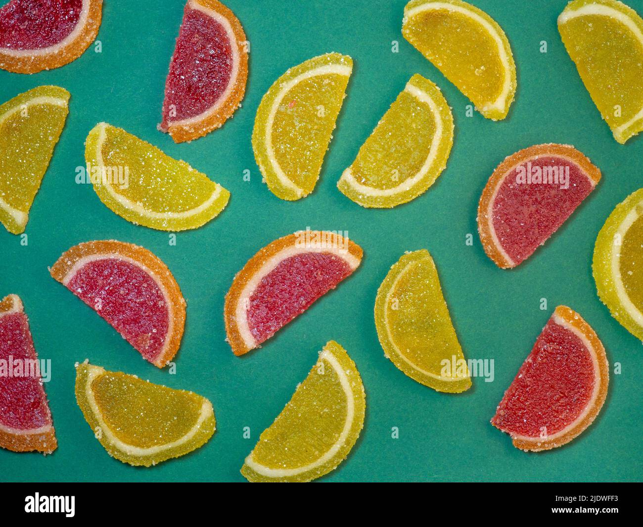 Fruit jelly in the form of orange slices on a green surface. Background from sweets. Background
