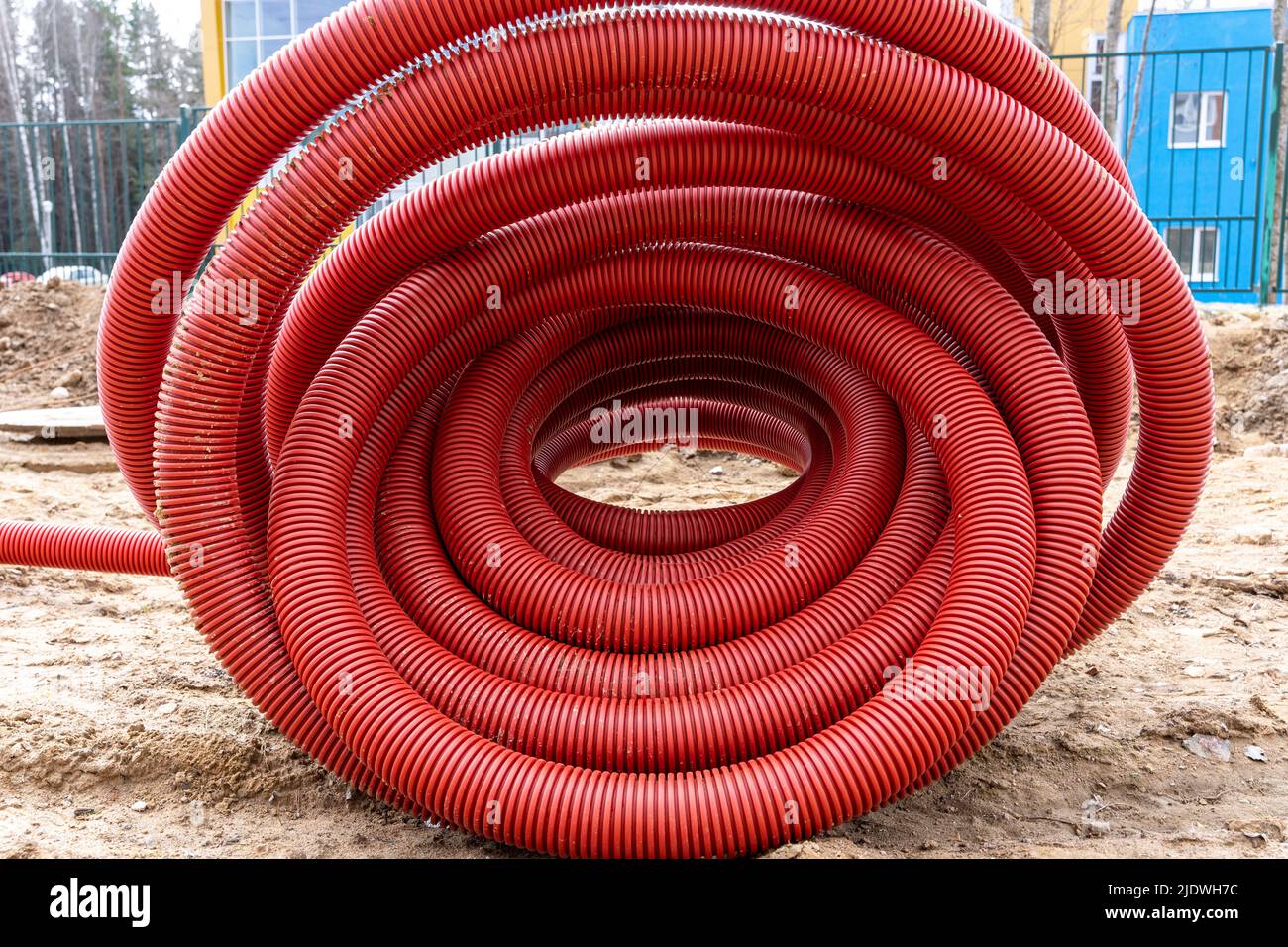 rolled up red corrugated PVC pipe for laying electrical cables Stock Photo