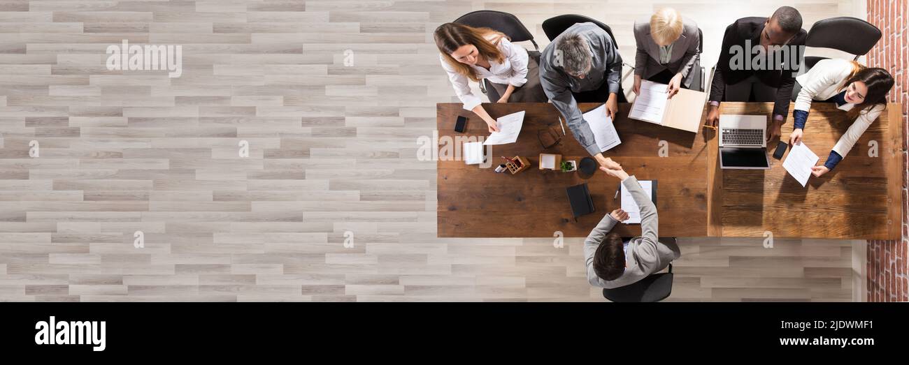 Overhead View Of Business Partner Shaking Their Hands In Meeting Stock Photo