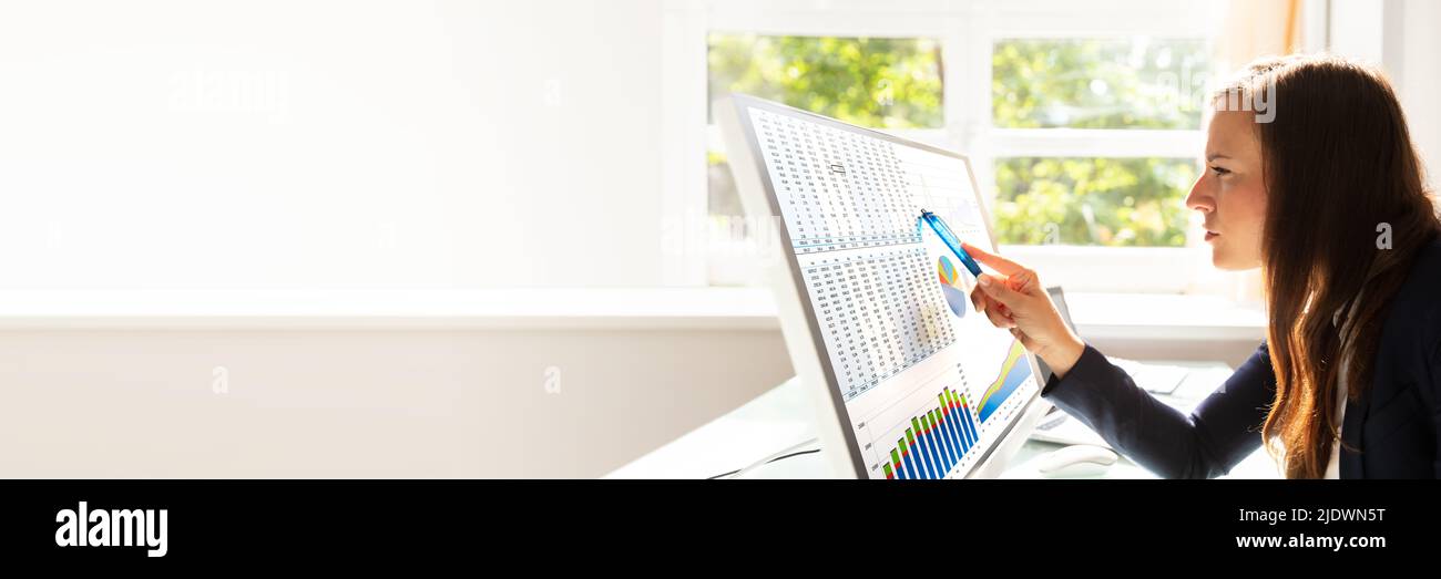Young Businesswoman Analyzing Graphs On Computer At Workplace Stock Photo