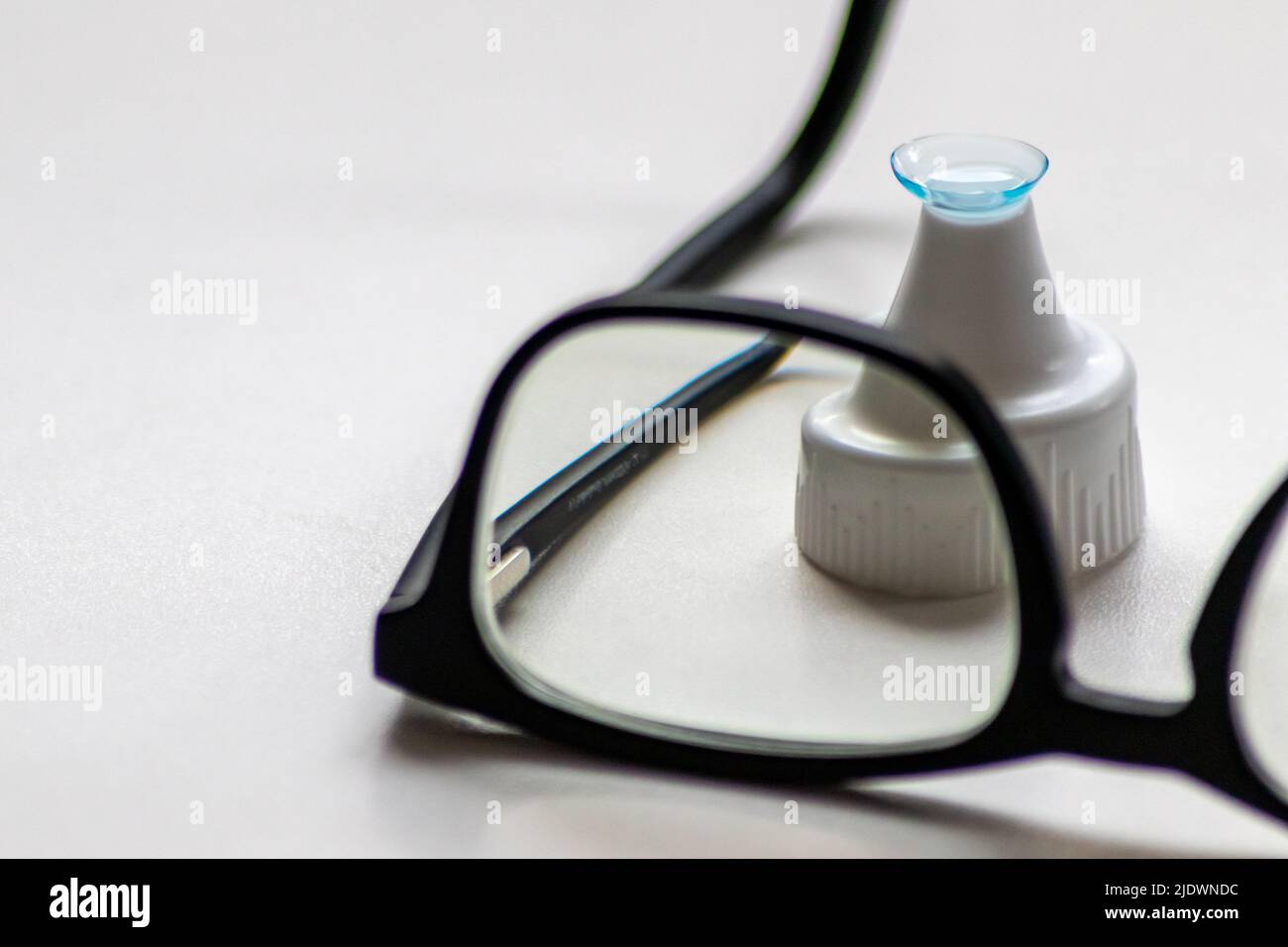 Blue contact lens through black eyeglasses shows different eyewear to correct farsightedness and nearsightedness by optometry or eye doctor myopia Stock Photo