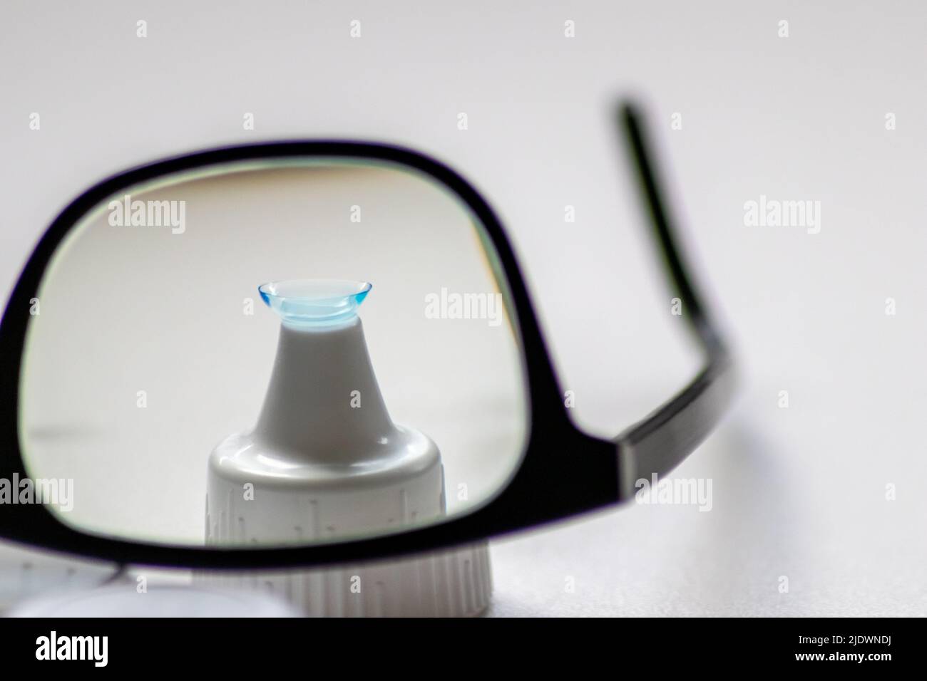 Blue contact lens through black eyeglasses shows different eyewear to correct farsightedness and nearsightedness by optometry or eye doctor myopia Stock Photo