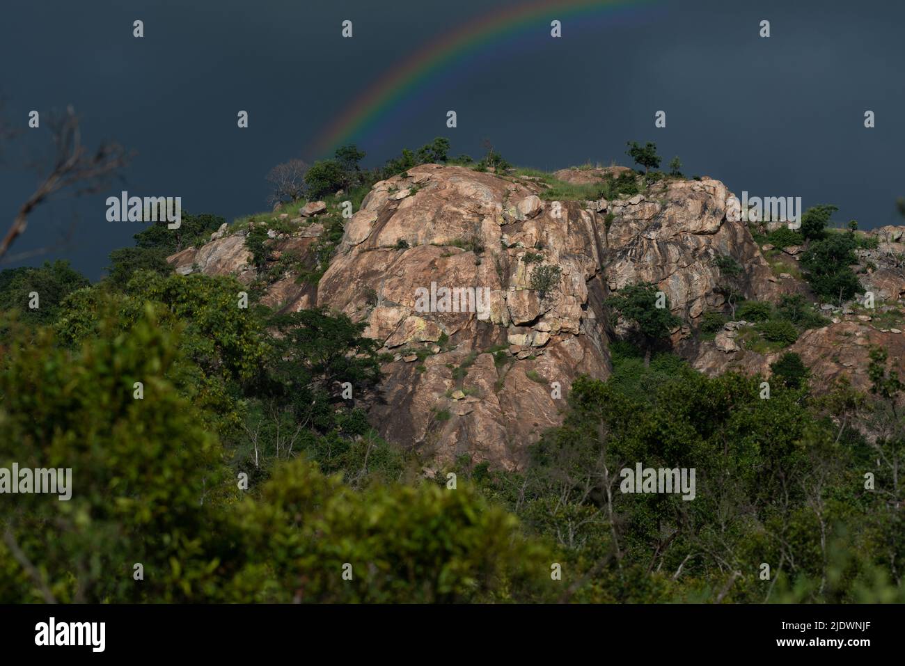 Rainbow behind a rocky outcrop in the Kruger National Park Stock Photo