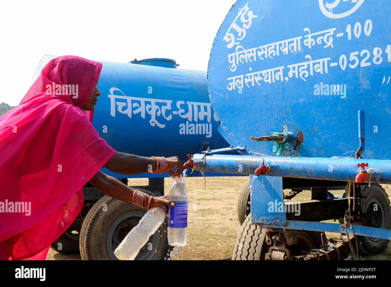 INDIA, Uttar Pradesh, Bundelkhand, Mahoba, water scarcity, women in pink saree at blue water tank filling plastic bottle with drinking water, during a rally of women movement Gulabi Gang Stock Photo