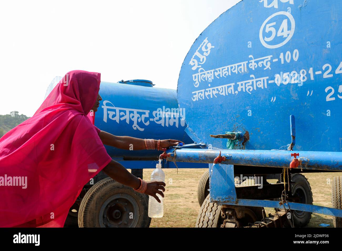 INDIA, Uttar Pradesh, Bundelkhand, Mahoba, water scarcity, women in pink saree at blue water tank filling plastic bottle with drinking water, during a rally of women movement Gulabi Gang Stock Photo