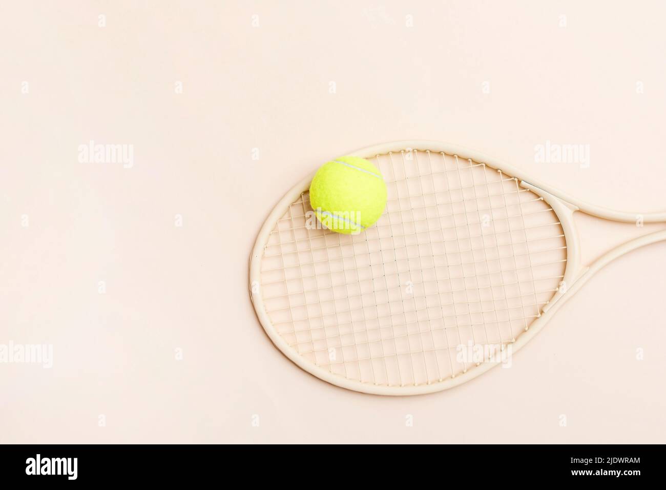 Beige tennis racket and yellow ball on beige background. Horizontal sport theme poster, greeting cards, headers, website and app Stock Photo