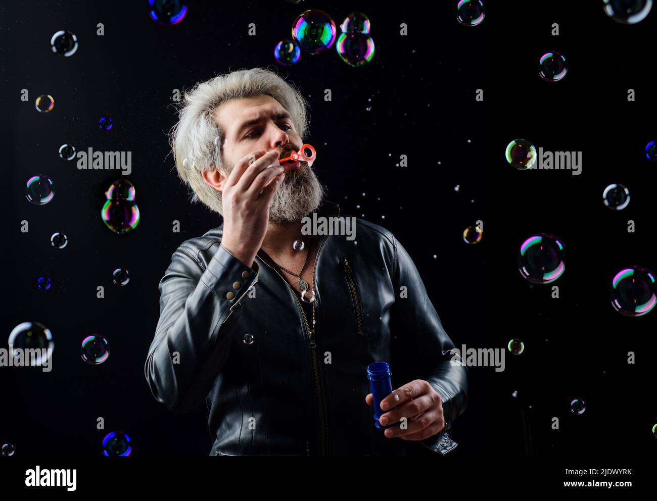 Bearded man blowing soap bubbles. Good mood. Childhood and Happiness concept. Play with bubble. Stock Photo
