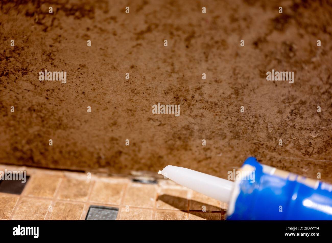 Silicone caulk being applied along a tile joint in a bathroom shower