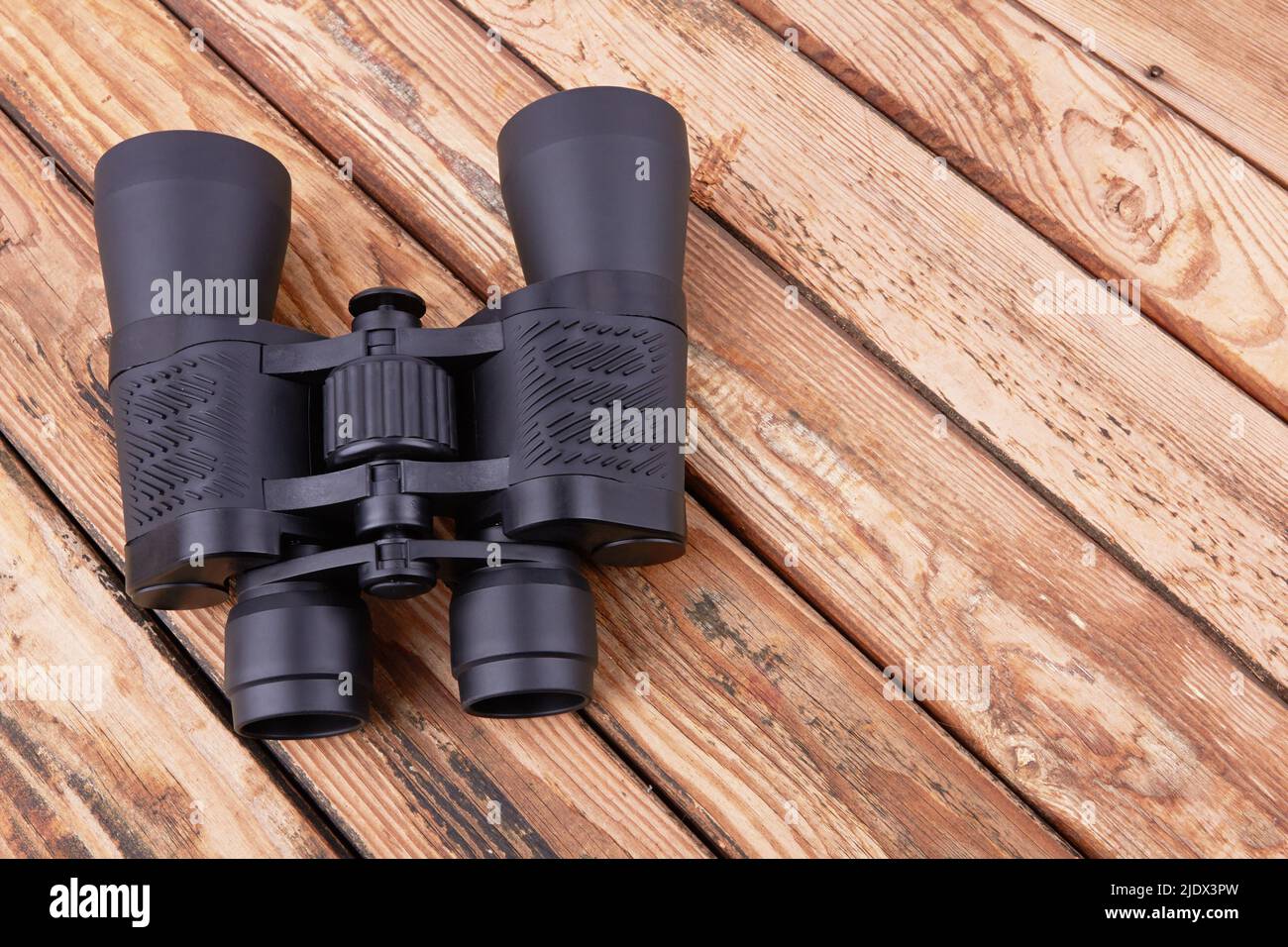 Black binoculars on a wooden surface Stock Photo